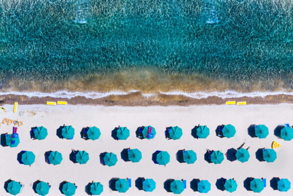 Blaues Meer, Strand mit blauen Sonnenschirmen als Symbolfoto für Kommunikationsmodelle