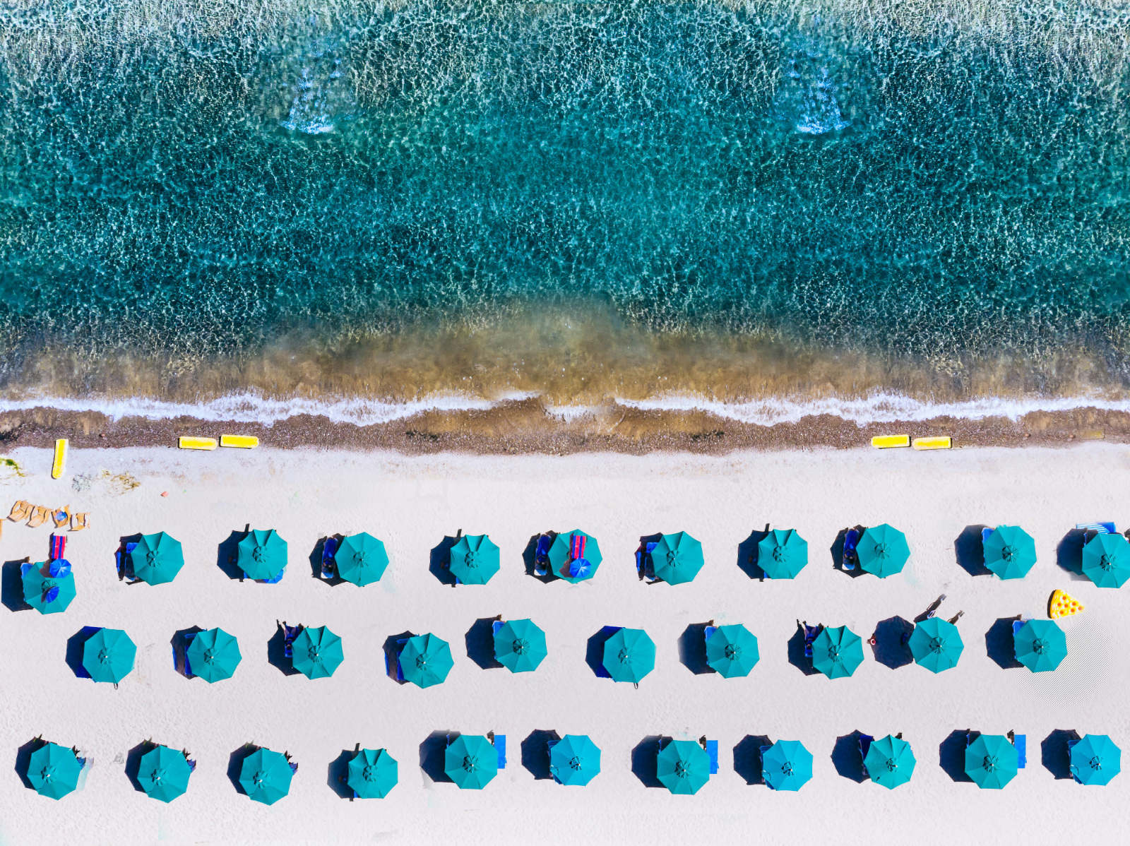 Blaues Meer, Strand mit blauen Sonnenschirmen als Symbolfoto für Kommunikationsmodelle